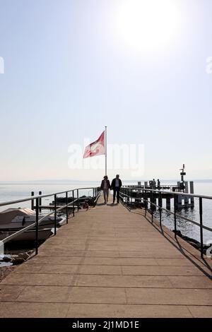 middle aged couple walking on edge of pier with a Swiss flag Stock Photo