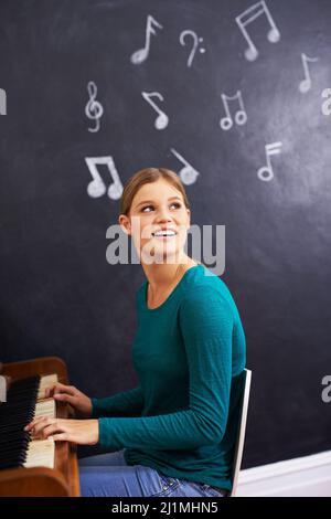 Making music. Shot of a woman playing the piano against a background of musical notes. Stock Photo