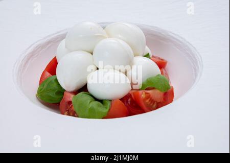 Italian food, tasty caprese salad with red cherry tomatoes, white mozzarella cheese and green basil leaves Stock Photo