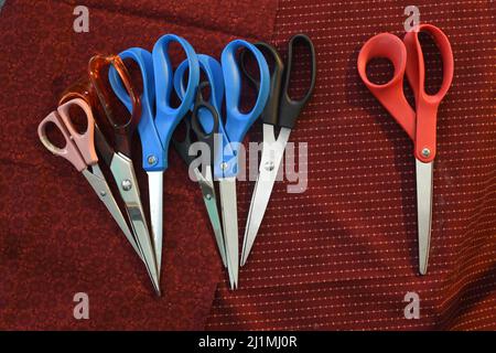 A grouping of scissors on a maroon background Stock Photo