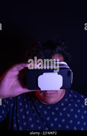 Young latin man using Virtual Reality VR Headset 3D Glasses. Dark backdrop. Low key. Copy space Stock Photo
