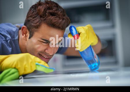 I will get this squeaky clean. Shot of a young man doing household chores. Stock Photo