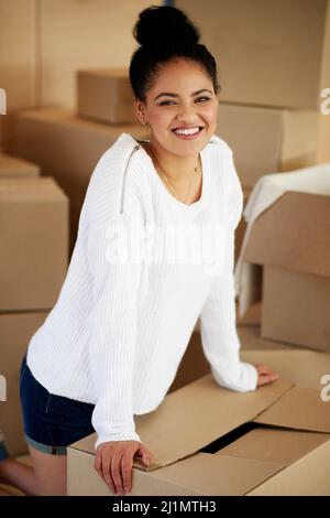 New house, here I come. Portrait of a happy young woman kneeling among cardboard boxes while moving house. Stock Photo