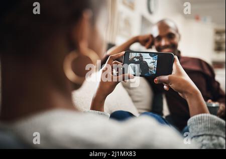 Shell always give me a reason to smile. Shot of a handsome young man posing for the camera while his girlfriends takes pictures of hime with her Stock Photo