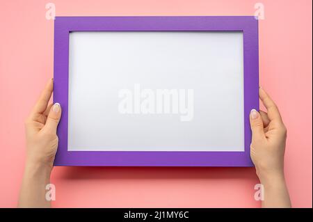 Holding frame mockup. Photo Mockup. Woman hands hold blue frame. For frames and posters design. Frame size A4. on pink background. blank photo frame b Stock Photo