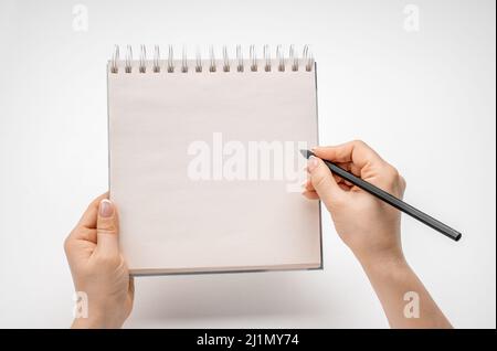female hands writing in mockup notepad isolated on white. Woman writing in notepad. Mockup notepad with woman hands on white table background Stock Photo