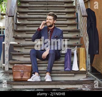 Dressed in his best for a day of retail therapy. Shot of a well dressed young man using his phone on a shopping spree. Stock Photo