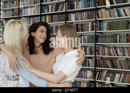 Friends meets in library hugging glad to see each other Stock Photo