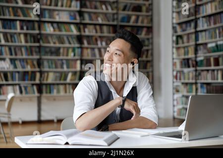 Smiling Korean guy sit at table studying in library Stock Photo