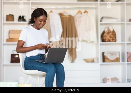 African American Lady Using Laptop And Smartphone Shopping At Home Stock Photo
