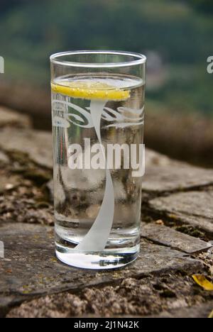 Glass with fresh sparkling water with lemon slice outdoors in autumn. Stock Photo