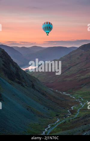 Digital composite image of hot air balloons over Epic landscape image of view down Honister Pass to Buttermere from Dale Head in Lake District during Stock Photo