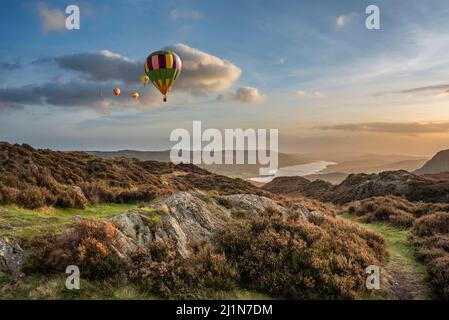 Digital composite image of hot air balloons over Epic Autumn sunset landscape image from Holme Fell looking towards Coniston Water in Lake District Stock Photo