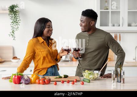 Affectionate Black Couple Drinking Red Wine In Kitchen While Preparing Lunch Together Stock Photo