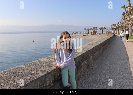 Beautiful little girl smiling at outside. She posing in front of lake. Trees background. Copy paste, text space. Stock Photo