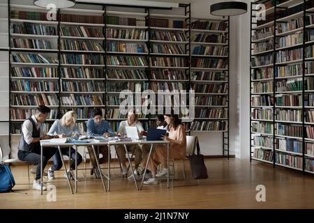 Group of multiracial students sit at table in library Stock Photo