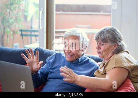 happy grandparents making a video call with a modern device, elder couple using laptop and tech application to communicate, modern technology helping Stock Photo