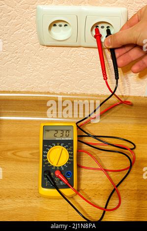 Metering socket voltage with digital multimeter. Stock Photo