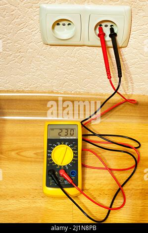 Metering socket voltage with digital multimeter. Stock Photo