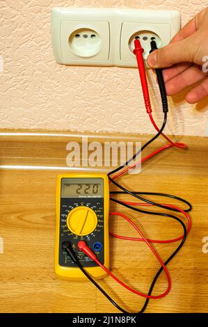 Metering socket voltage with digital multimeter. Stock Photo