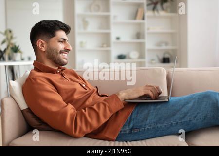 Portrait of smiling Arab man using pc at home Stock Photo