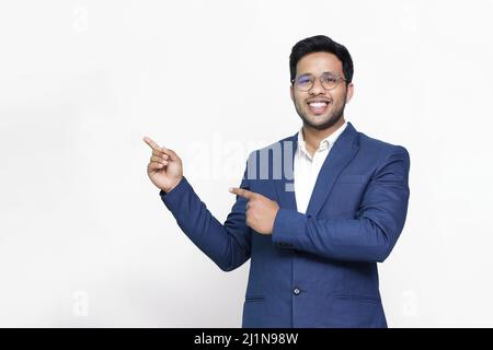 Portrait of a happy businessman pointing finger away over white background. Stock Photo