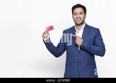 Young smiling man in pointing on credit card. Stock Photo