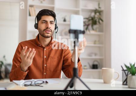 Arab man having videocall using cellphone on tripod Stock Photo
