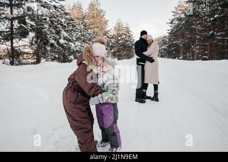 mom and dad and two sisters hugging in the winter snowy forest Stock Photo