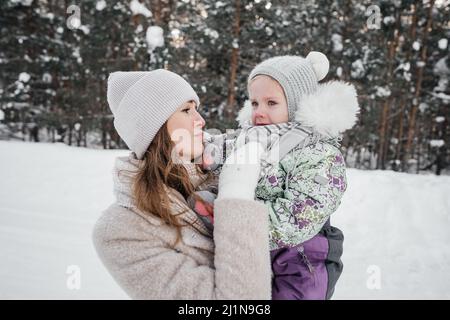 the baby cries and is sad, the mother holds the child in her arms and soothes Stock Photo