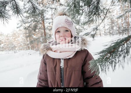girl in warm clothes in the winter forest next to the Christmas tree Stock Photo
