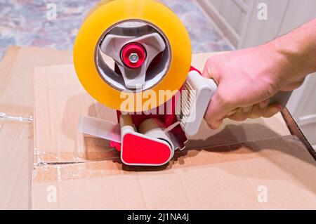 Packaging parcels with scotch tape dispenser close-up Stock Photo