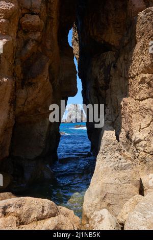 A breach made in a cliff through which a turquoise blue sea can be seen. Stock Photo