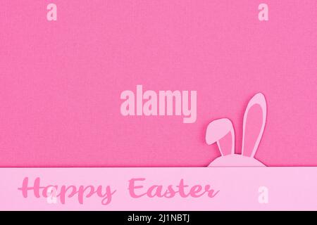 Bunny rabbit ears made of pink paper on pink background. Paper cut of colorful easter rabbit, and blue egg shape. Happy easter greeting card template. Stock Photo