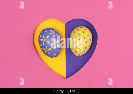Creative Easter layout with Painted Easter eggs on a pink paper background. Spring nature Easter holiday minimal concept. The shape of the heart is fl Stock Photo