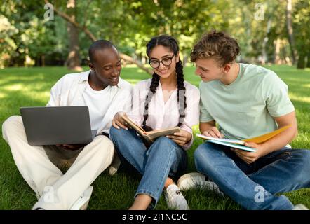 Multiracial students friends learning together, reading books and using laptop computer, sitting in university campus Stock Photo