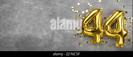 Yellow foil balloon number, number forty four concrete background. Greeting card with the inscription 44. Anniversary concept. for anniversary Stock Photo