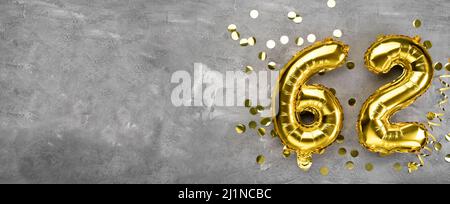 Yellow foil balloon number, number sixty two on a concrete background. Greeting card with the inscription 62. Anniversary concept. for anniversary Stock Photo