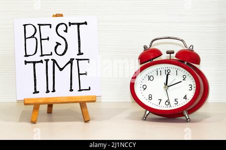 best TIME written in a notebook near a white alarm clock. Stock Photo