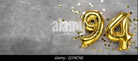 Yellow foil balloon number, number ninety-four on a concrete background. Greeting card with the inscription 94. Anniversary concept. for anniversary Stock Photo