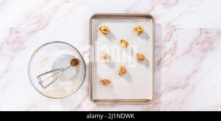 Scooping cookie dough with dough scoop into a baking sheet lined with  parchment paper to bake soft oatmeal raisin walnut cookies Stock Photo -  Alamy