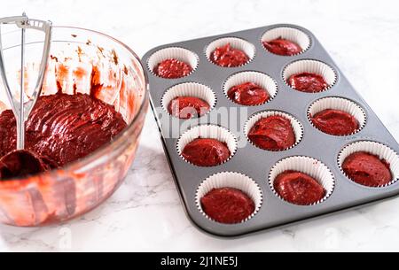 https://l450v.alamy.com/450v/2j1ne5j/scooping-cupcake-dough-with-dough-scoop-into-cupcake-pan-lined-with-foil-liners-to-bake-red-velvet-cupcakes-with-white-chocolate-ganache-frosting-2j1ne5j.jpg