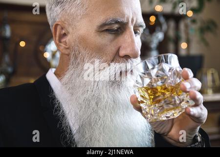 Handsome bearded senior man with a glass of whiskey Stock Photo