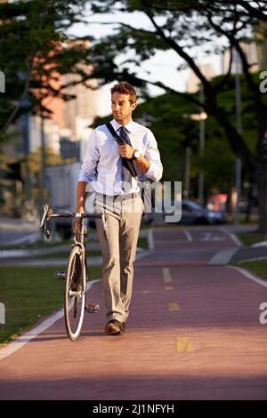 Keeping his carbon footprint as low as possible. Shot of a businessman commuting to work with his bicycle. Stock Photo