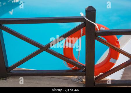 Red lifebuoy near the pool on a wooden pier. Stock Photo