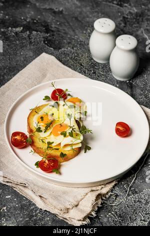 Fried eggs on toast, cherry tomatoes and arugula microgreens. Delicious and healthy breakfast recipe. Vertical shot Stock Photo