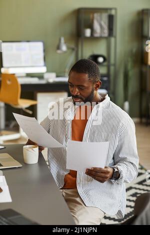 Vertical portrait of modern black businessman working at home office and analyzing documents Stock Photo