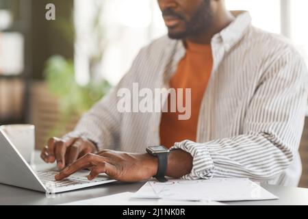 Close up of modern black businessman typing at keyboard while working in home office, copy space Stock Photo