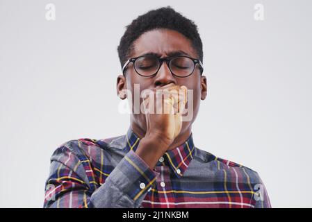 Coming down with the flu. Studio shot of a handsome young man coughing against a grey background. Stock Photo