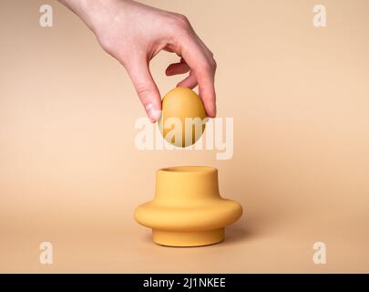 Woman hand putting beige egg in cup. Egg holder and server. Easter concept. High quality photo Stock Photo
